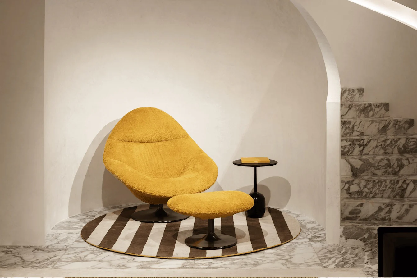 A stylish Fendi Groove & Groovy armchair with yellow sheepskin upholstery, paired with a matching ottoman, set on a striped rug, creating a vibrant and inviting seating area.