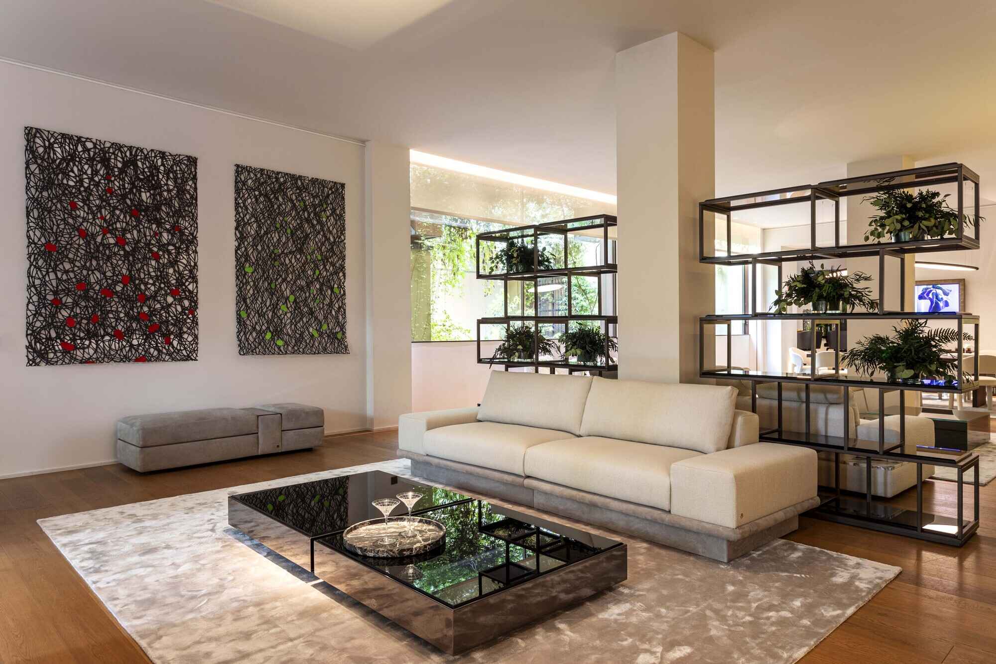 A sophisticated Luxence Luxury Living interior featuring a plush cream sofa, a sleek glass coffee table, and vibrant artwork, complemented by a stylish shelving unit adorned with greenery.